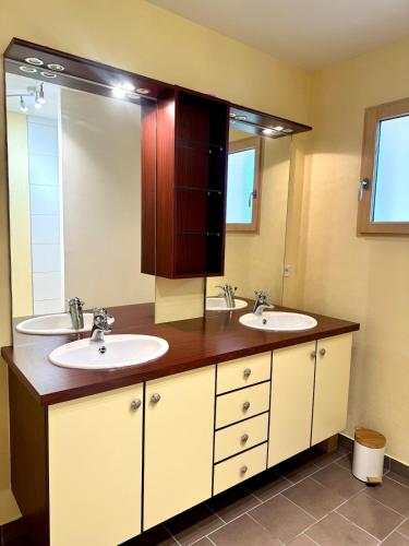 une salle de bain avec deux lavabos et un grand miroir dans l'établissement Jolie maison - 15 Mins des plages, à Pleslin-Trigavou