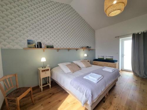 a bedroom with a large bed and a chair at La Ferme des Galoches in Villemontais