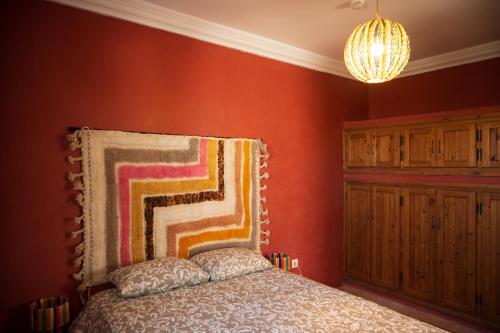 a bedroom with red walls and a bed and a chandelier at The Mogador's Oasis in Akermoud