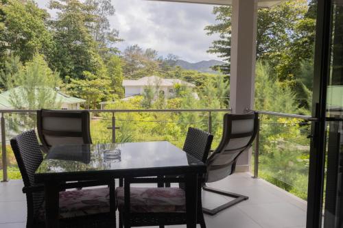 a table and chairs on a balcony with a view at Palm Holiday Apartments in Grand'Anse Praslin