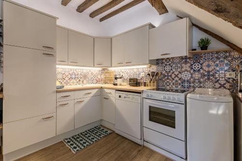 une cuisine avec des armoires blanches et des appareils électroménagers blancs dans l'établissement La Goélette - Entre Port & Plage - Cosy, à Dieppe