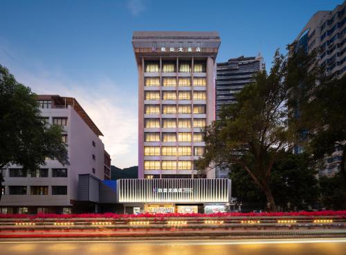 un immeuble de grande hauteur illuminé dans une ville dans l'établissement 凯旋龙酒店广州区庄地铁站店 交易会期间提供免费穿梭巴士, à Canton