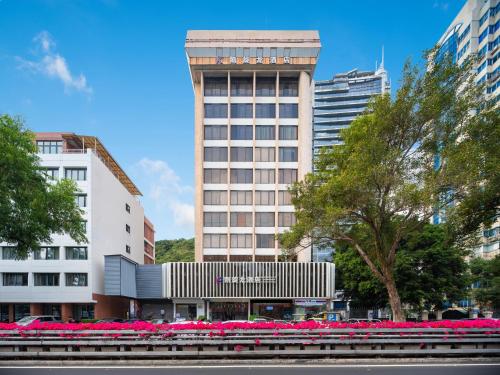 un grand bâtiment avec des fleurs roses devant dans l'établissement 凯旋龙酒店广州区庄地铁站店 交易会期间提供免费穿梭巴士, à Canton