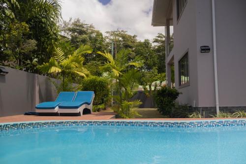 a pool with a blue bench next to a house at Palm Holiday Apartments in Grand'Anse Praslin