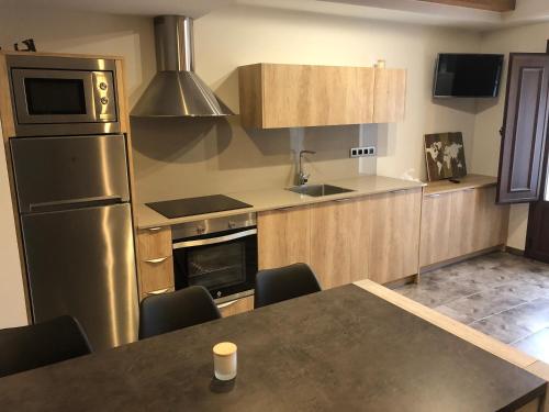 a kitchen with a table and a stainless steel refrigerator at Casa FOR in Labuerda
