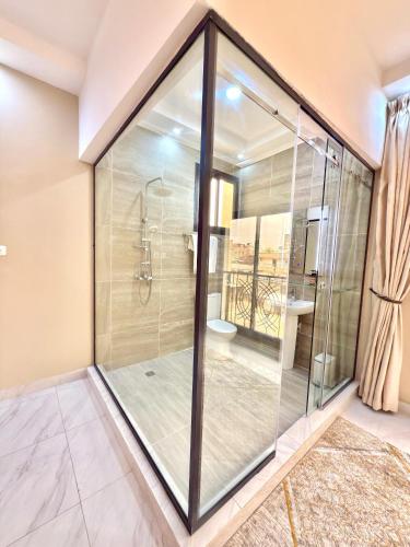 La salle de bains est pourvue d'une cabine de douche en verre. dans l'établissement Ken-JResidence, à Douala