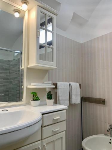 Un baño blanco con lavabo y espejo. en Dimora Artus - Home Salento com, en Ugento
