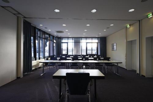 a large room with tables and chairs and windows at IntercityHotel Freiburg in Freiburg im Breisgau