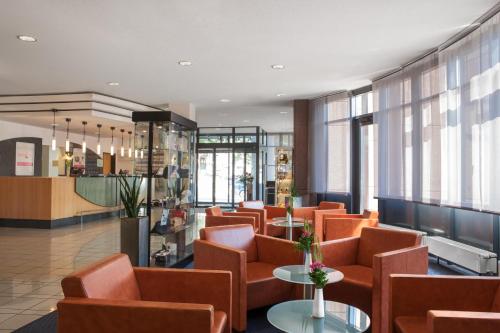 a waiting room with orange chairs and tables at IntercityHotel Freiburg in Freiburg im Breisgau