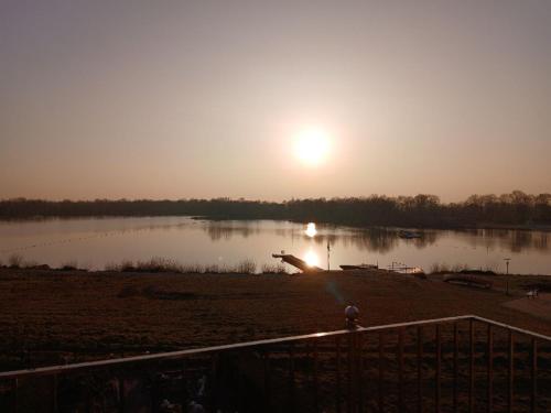 a view of a lake with the sun in the sky at Strandperle Timmel in Großefehn 