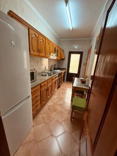 a kitchen with a white refrigerator and a table at Casa Rural NIEVES piscina privada in Hinojares