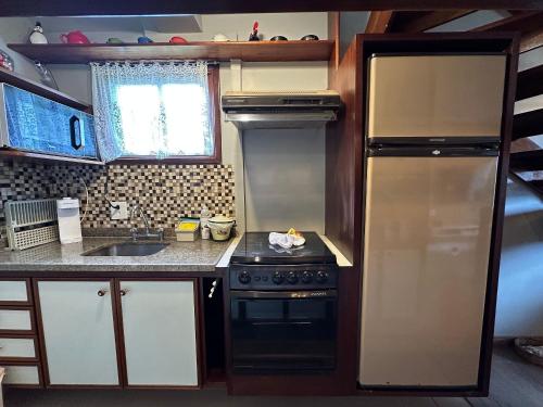 a small kitchen with a stove and a refrigerator at Flat para 6 pessoas no Home Green Home in Campos do Jordão