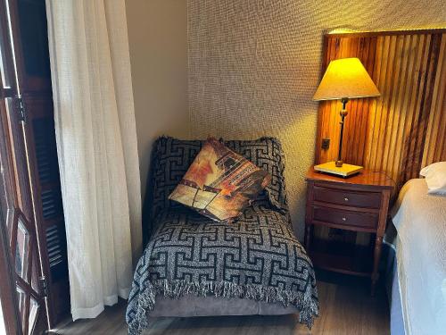 a bedroom with a bed with a pillow and a lamp at Flat para 6 pessoas no Home Green Home in Campos do Jordão