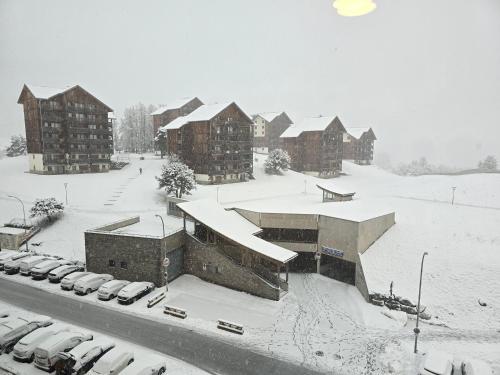 un bâtiment enneigé avec des voitures garées dans un parking dans l'établissement Appt 5p 5ème étage chez Locasoleil, à Saint-Étienne-en-Dévoluy