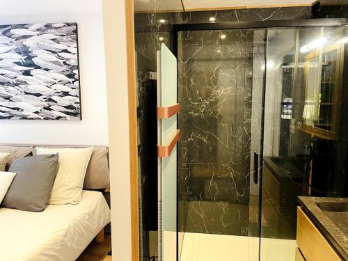 - une douche en verre dans le salon avec un canapé dans l'établissement L'Atelier de Mer, à Perros-Guirec