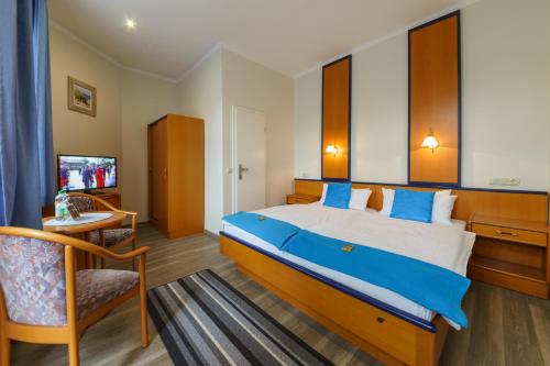 a bedroom with a bed and a chair and a television at Haus Alexander in Heringsdorf