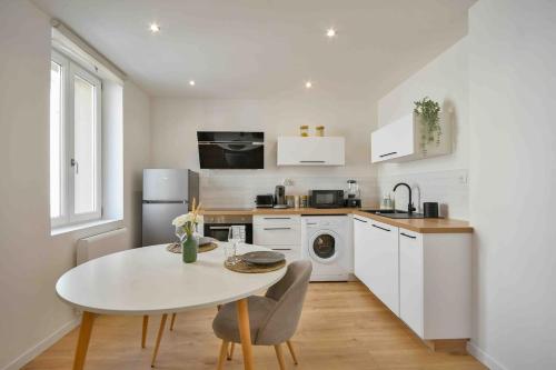 une cuisine avec une table blanche et une table et des chaises dans l'établissement Superbe appartement - Cosy à 10 min Centre ville, à Schiltigheim
