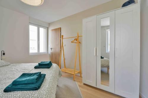 a bedroom with a bed with green towels on it at Superbe appartement - Cosy à 10 min Centre ville in Schiltigheim