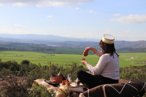 a woman sitting on top of a hill eating food at 1001-Nights Palace in Nebeur