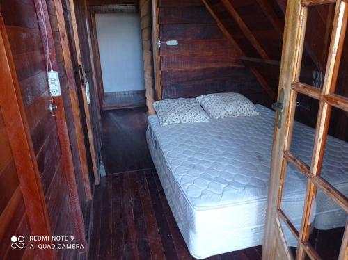 ein Schlafzimmer mit einem Bett in einer Holzhütte in der Unterkunft Chalé Boas Novas Piranguçu MG in Piranguçu