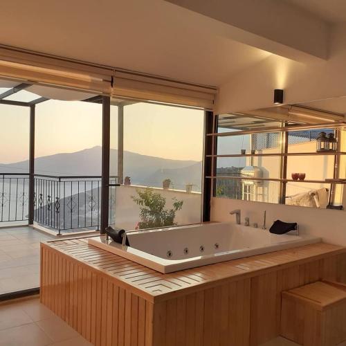 a large bath tub in a room with a balcony at Glennhouse in Kaş