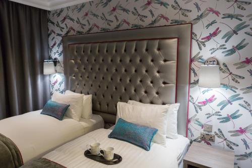 a hotel room with two beds and a wall with flowers at The Beverley Hotel London - Victoria in London