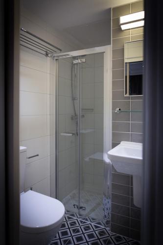 a bathroom with a shower and a toilet and a sink at The Beverley Hotel London - Victoria in London
