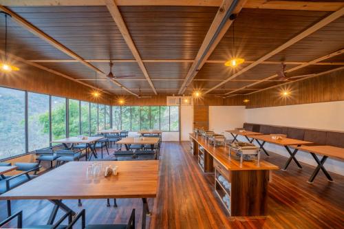 a restaurant with wooden tables and chairs and large windows at Perfectstayz The Jungle Resort, Shivpuri in Shivpuri