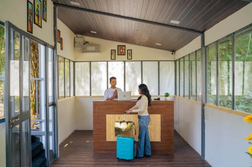 a woman with a suitcase and a man at a counter at Perfectstayz The Jungle Resort, Shivpuri in Shivpuri