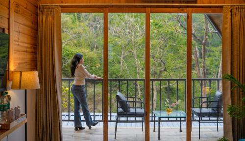 a woman standing on a balcony looking out the window at Perfectstayz The Jungle Resort, Shivpuri in Shivpuri