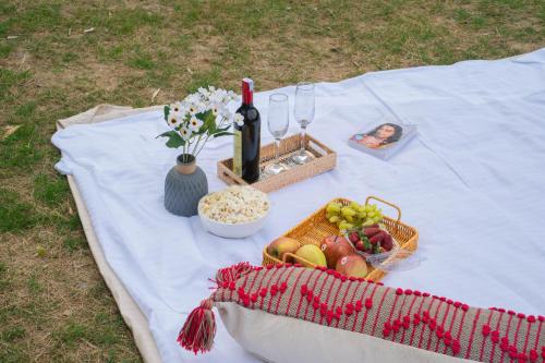 a picnic table with a basket of fruit and a bottle of wine at Perfectstayz The Jungle Resort, Shivpuri in Shivpuri