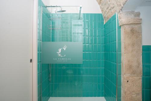 a green tiled shower with a sign on the wall at B&B La Camelia Luxury Suite in Terlizzi