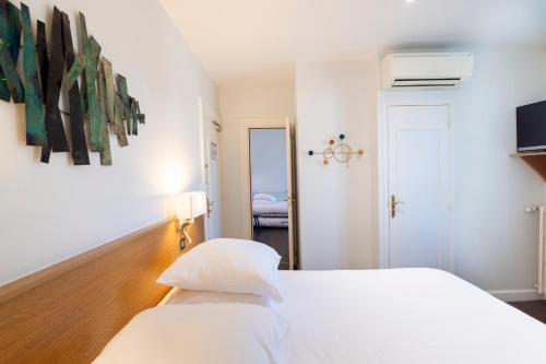 a white bedroom with a white bed and a room at Hotel De Paris Jaligny in Jaligny