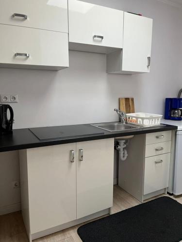 a kitchen with white cabinets and a black counter top at Apartamenty u Majki 2 in Frydman