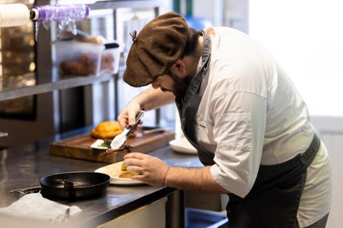 a chef preparing a plate in a kitchen at Hotel De Paris Jaligny in Jaligny