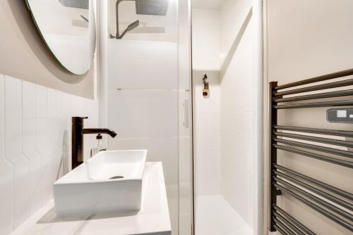 une salle de bain blanche avec un lavabo et un miroir dans l'établissement MARAIS - Rue au maire - Chinatown, à Paris