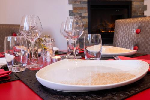 a table with wine glasses and a plate on a table at Hotel De Paris Jaligny in Jaligny