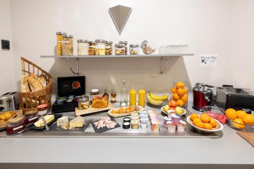a counter with many different types of food on it at Hotel De Paris Jaligny in Jaligny