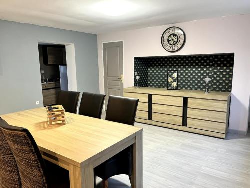 une salle à manger avec une table, des chaises et une horloge dans l'établissement La sérénité en baie de somme, à Béhen