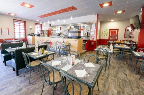 a restaurant with tables and chairs and a kitchen at Hotel De Paris Jaligny in Jaligny