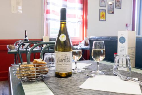a bottle of wine sitting on a table with glasses at Hotel De Paris Jaligny in Jaligny