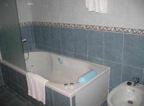 y baño con bañera y lavamanos. en Hotel Reyes De León, en Santa María del Páramo