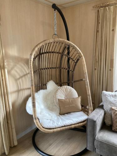 a wicker swing chair with a pillow in a living room at 6 persoons chalet op de Veluwe bij binnen en buiten zwembad in Arnhem