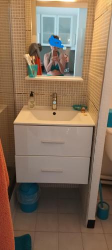 une femme prenant une photo d'un lavabo dans la salle de bains dans l'établissement Studio 26 M2 terrasse 6 M2 La Grande Motte, à La Grande Motte