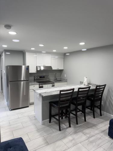 a kitchen with a counter with chairs and a refrigerator at Cozy Norment Forest Apartment in Lumberton