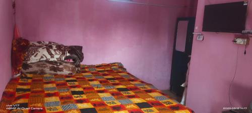 a bedroom with a bed and a pink wall at Brijendra Homestay in Khatīma