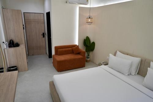 a bedroom with a bed and a brown chair at Hotel Elinor By Dazzling Hotels & Resorts in Agra