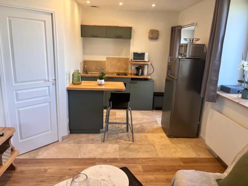 a kitchen with a refrigerator and a table with a counter at Charmante petite maison, à 5 mn de Blois in Vineuil