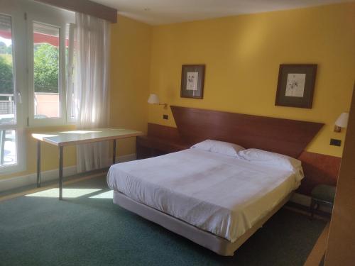a bedroom with a bed and a table and a window at Habitación triple con bañera y terraza HOTEL SUITE MIOÑO in Castro-Urdiales
