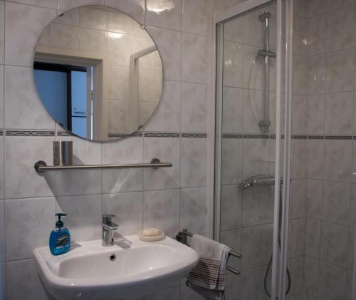 a bathroom with a sink and a shower with a mirror at Zeezand in Egmond aan Zee